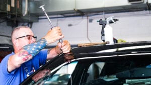 Conestoga Collision technician using paintless dent repair techniques.